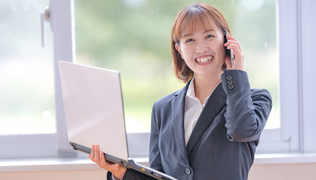 女性がPCをもって電話している写真